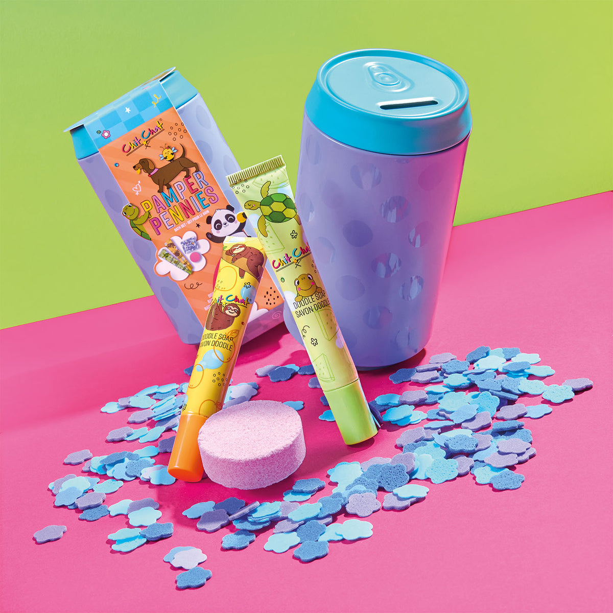 Colourful bath items including a purple money tin, colourful soaps, and confetti on a pink and green background.